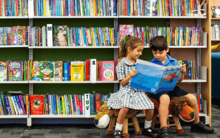 A photo showing two students from St Patrick's Catholic Primary School Summer Hill reading books in the library and on their way to 2025 NAPLAN results success